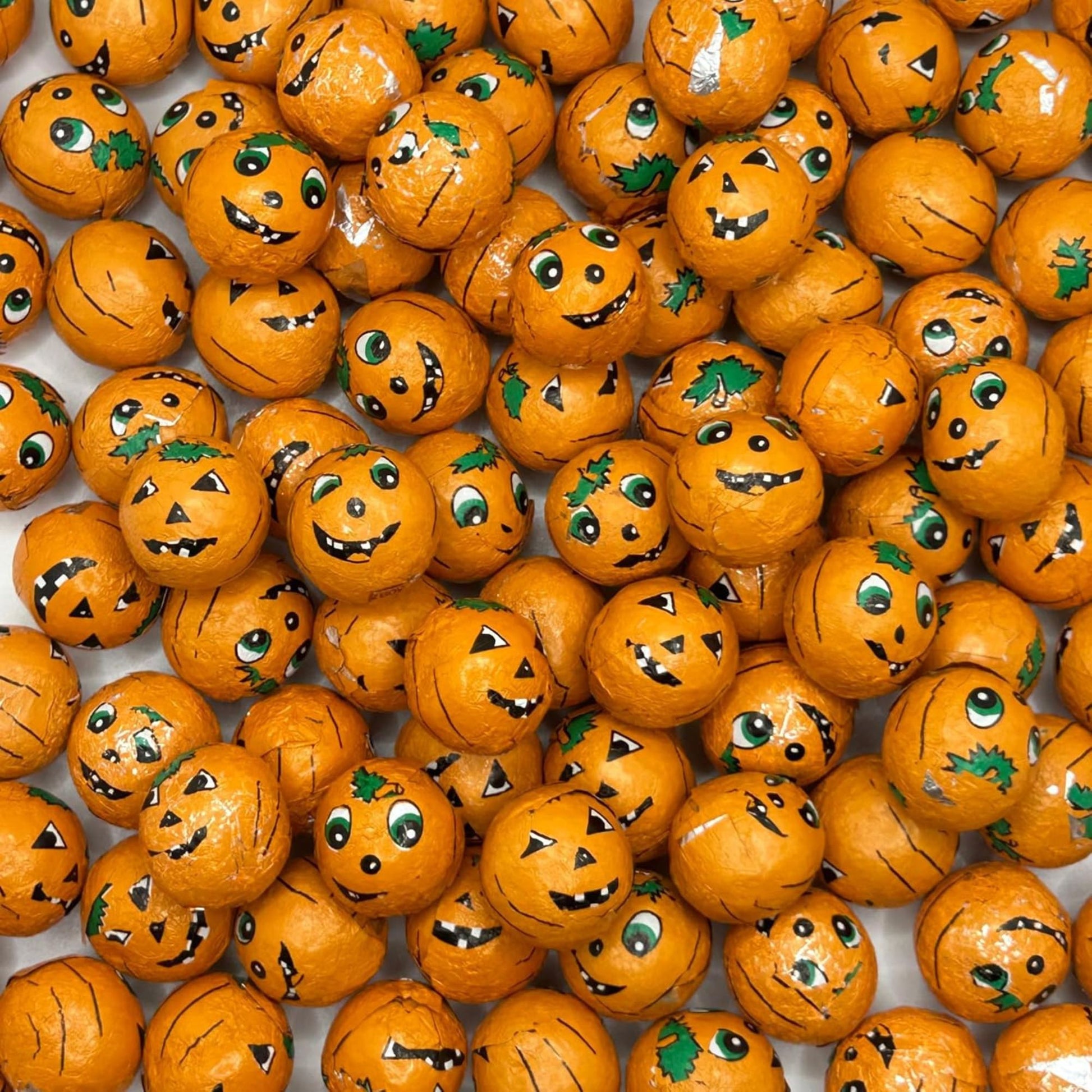 Orange pumpkin-shaped candies with faces on a white background