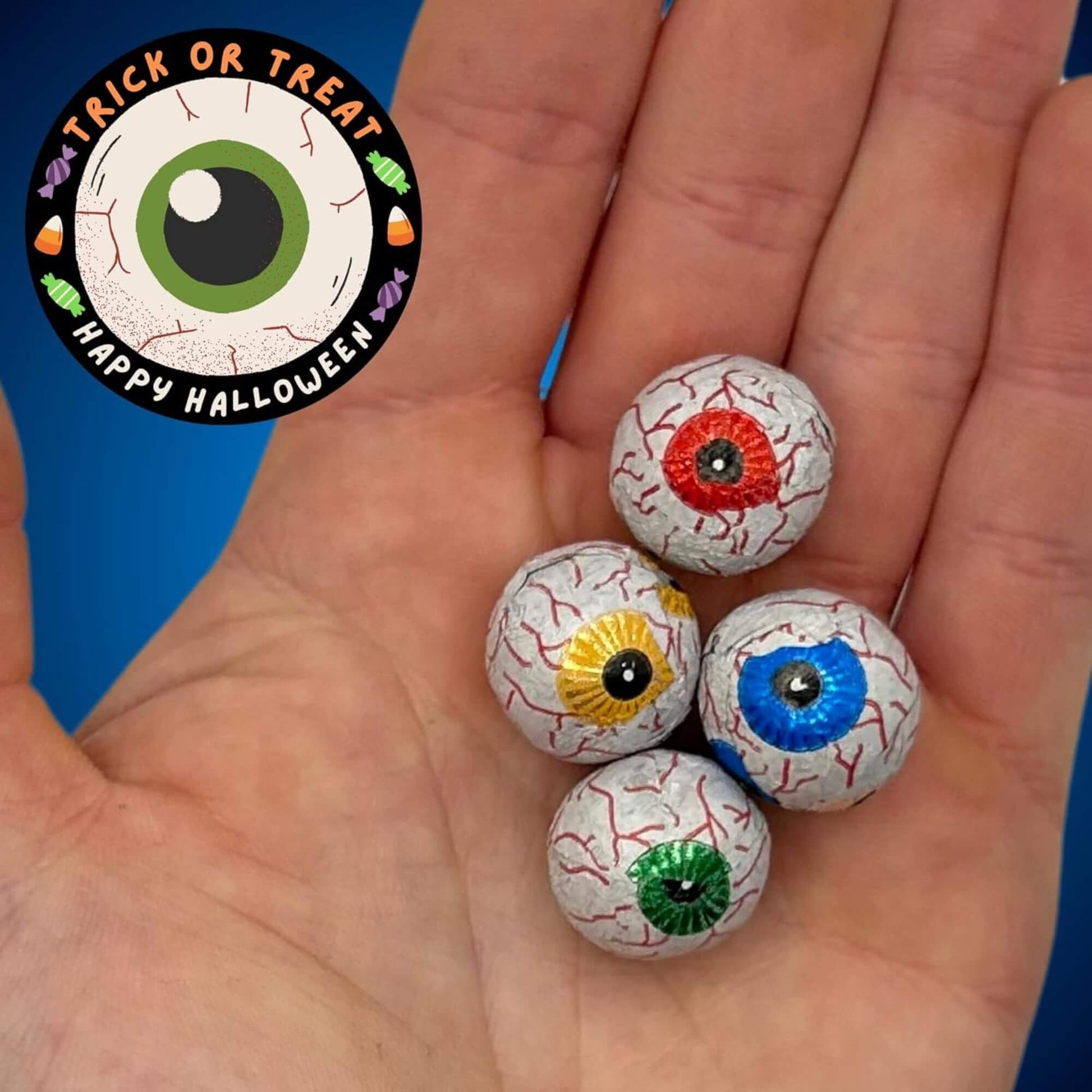 Colorful Halloween eyeball candies held in a hand with a 'Trick or Treat Happy Halloween' label.