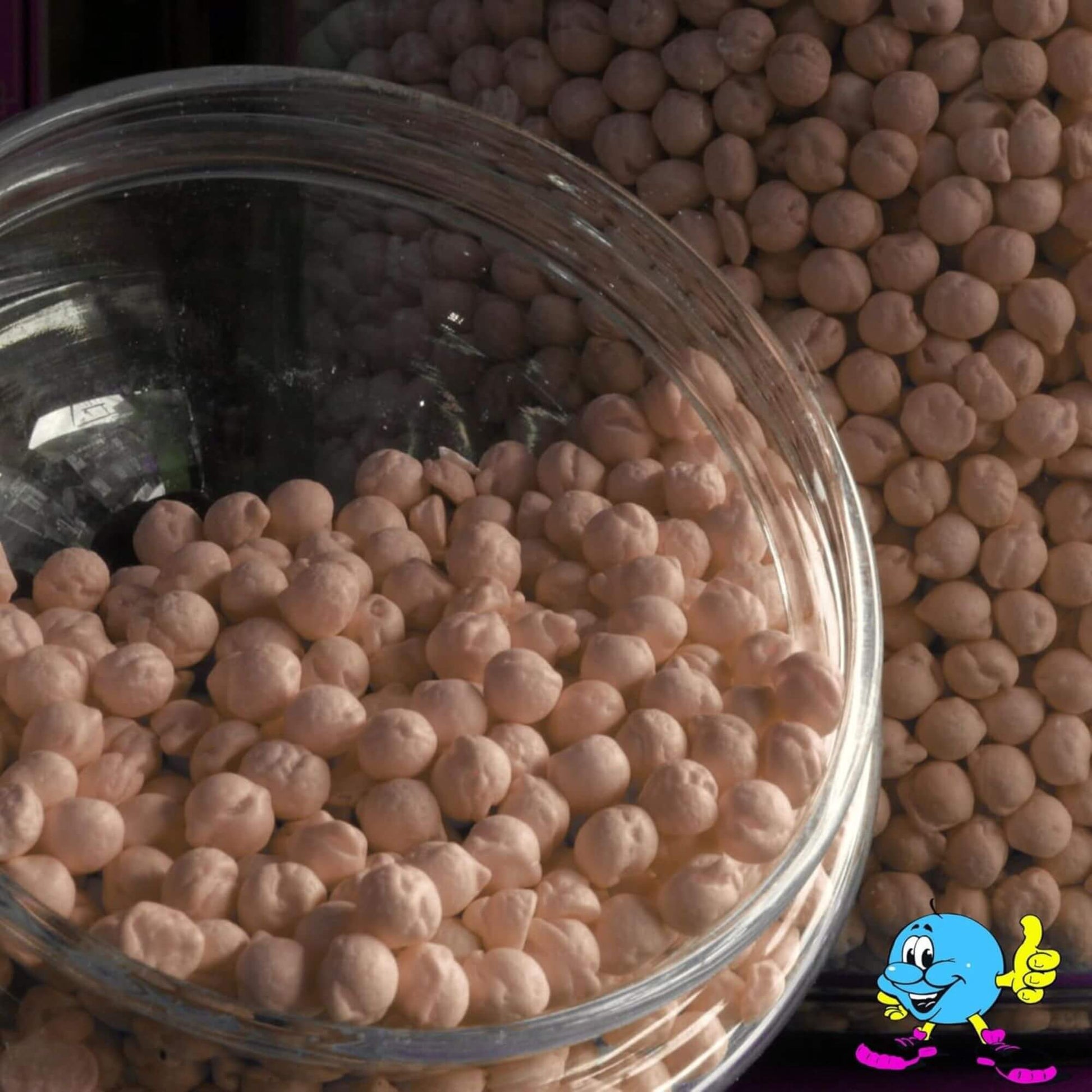 Glass jar filled with pinkish-beige beads on a dark background